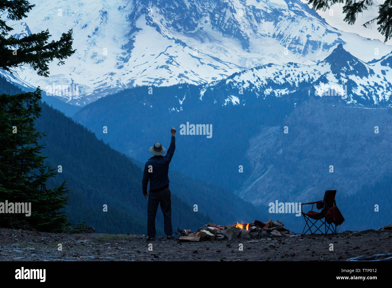 Uomo con il braccio alzato in piedi contro nevato mountain Foto Stock