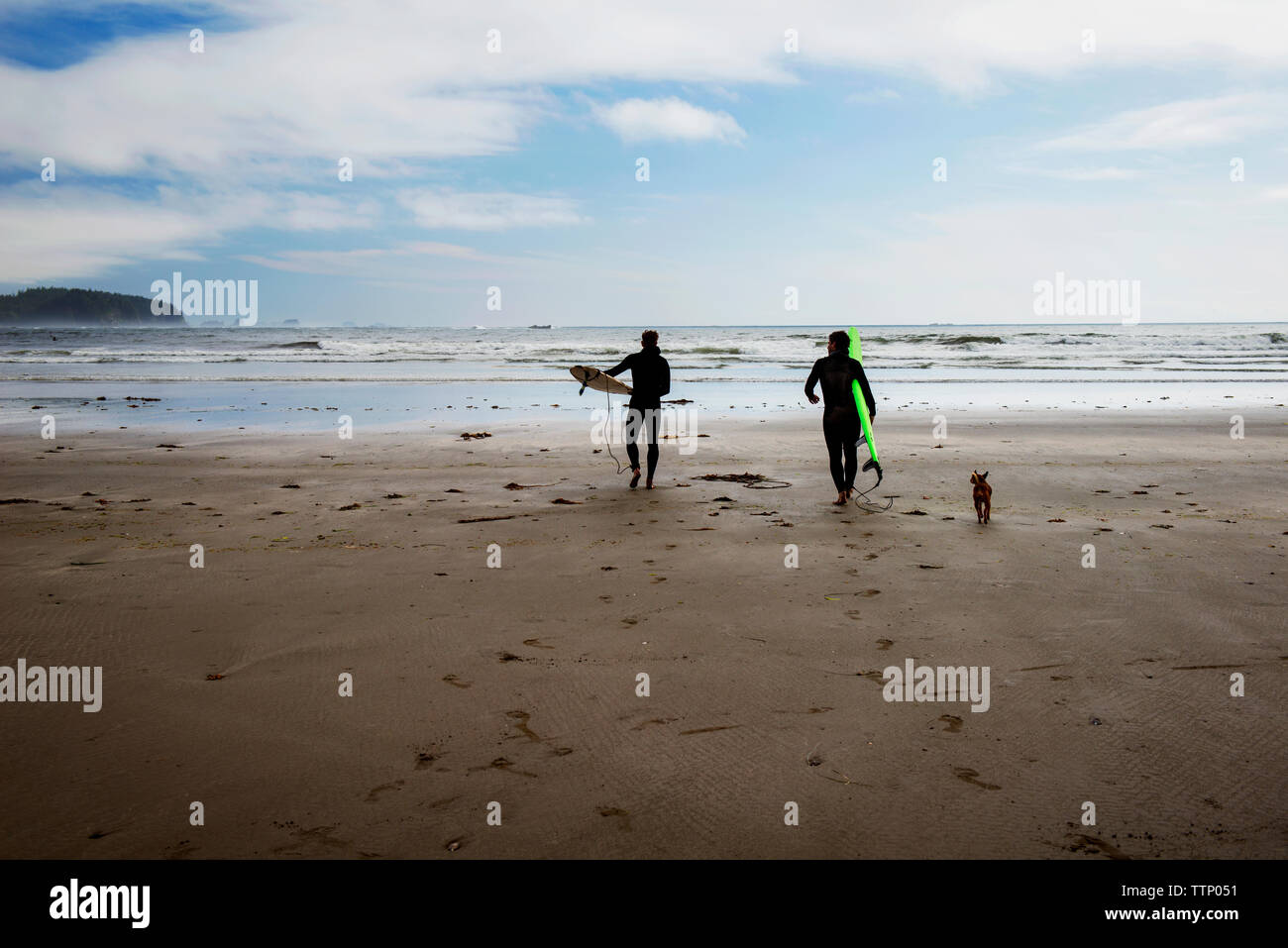 Surfers camminando sulla spiaggia contro sky Foto Stock