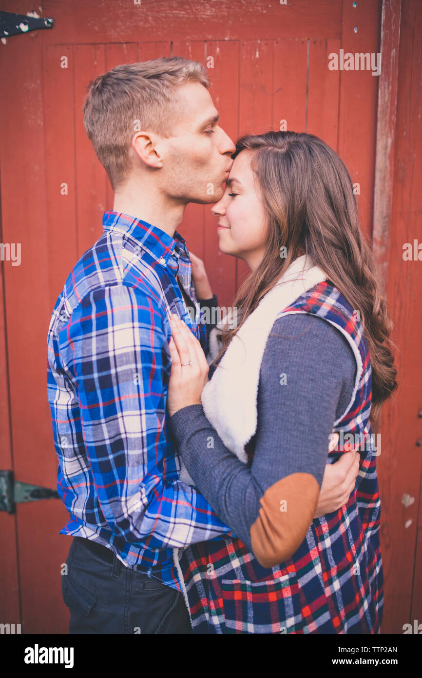 Il marito baciare moglie sul fronte dalla porta chiusa Foto Stock