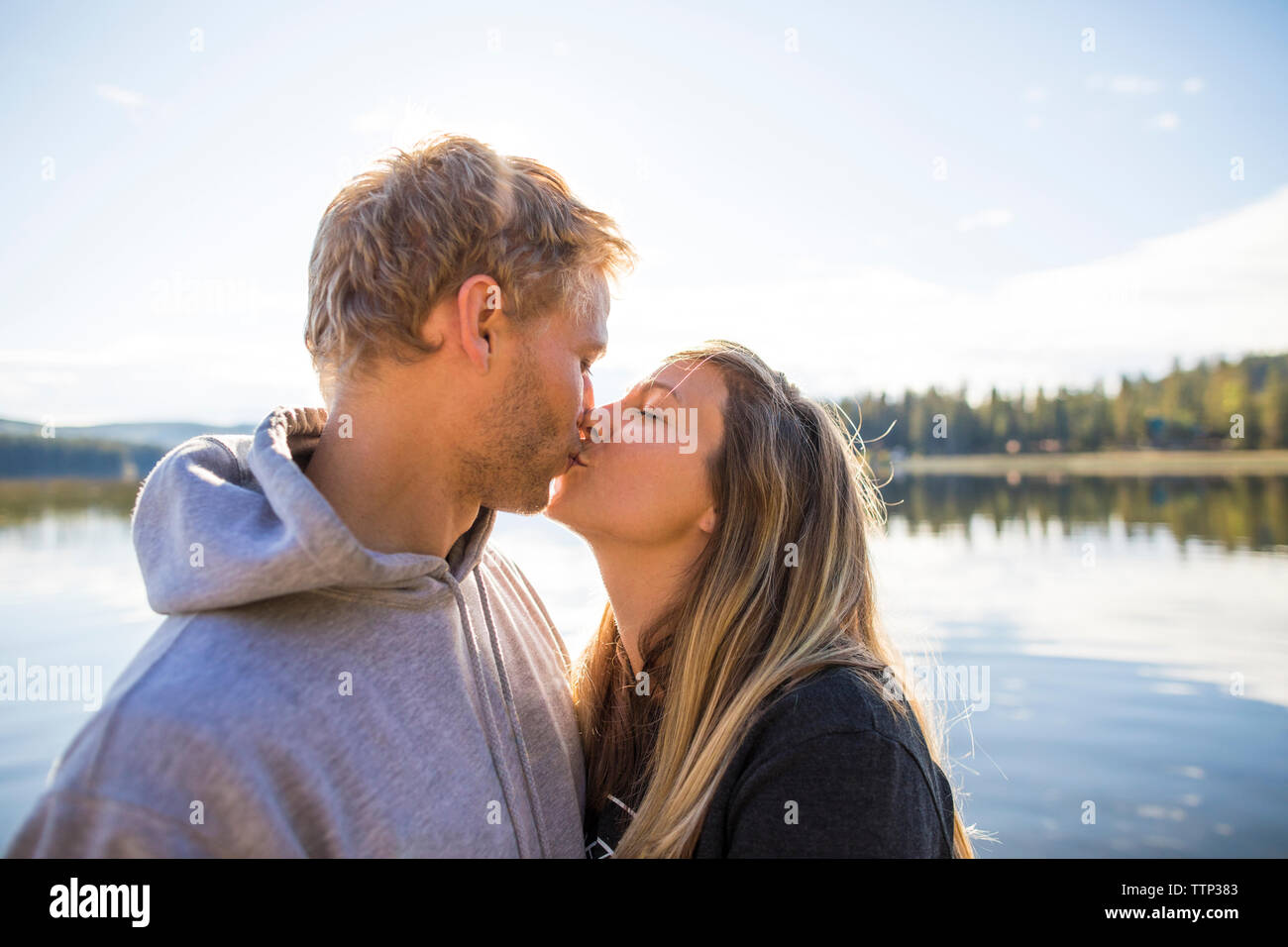 Amare giovane baciare sulla bocca contro il lago Foto Stock