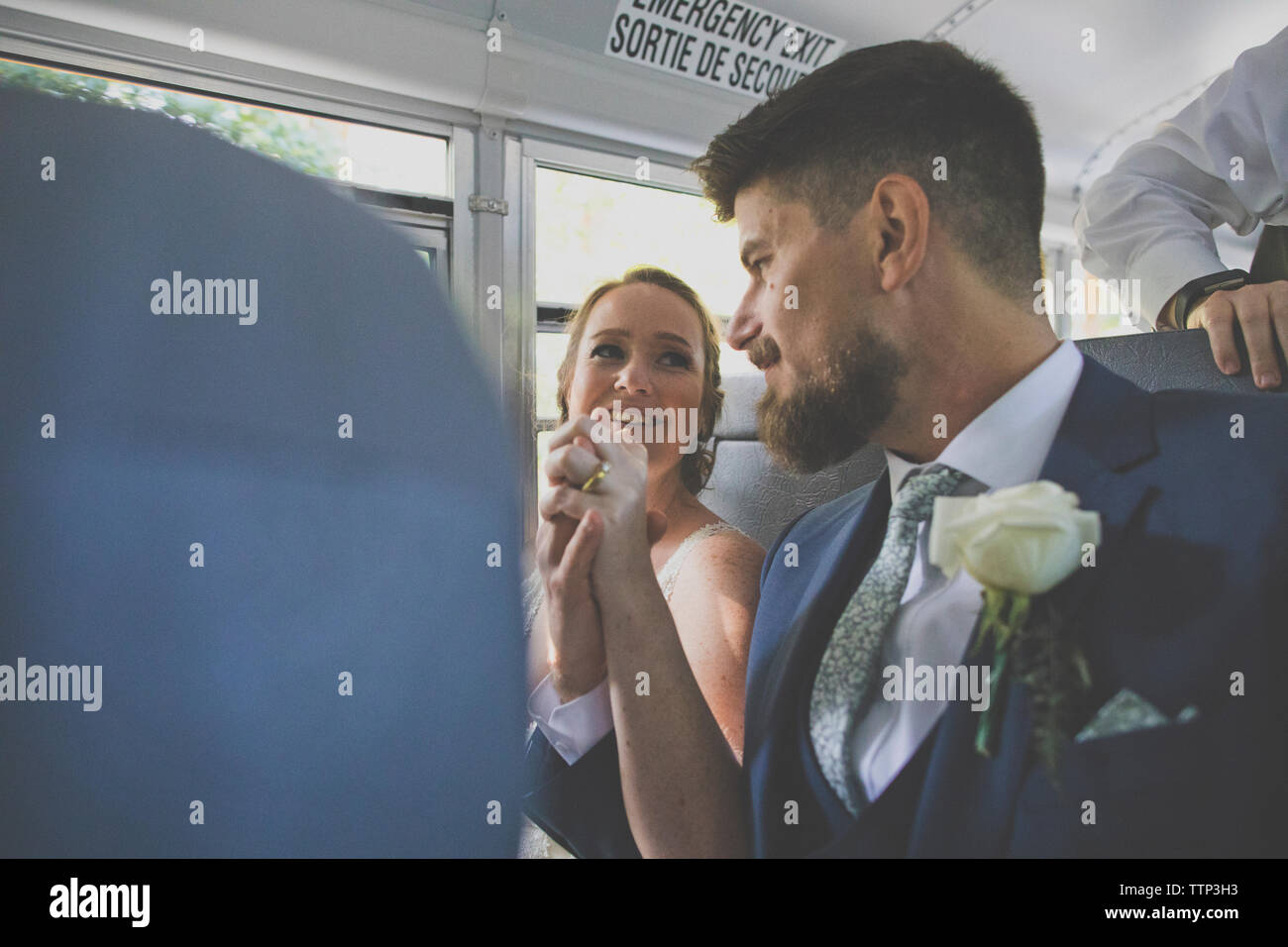 Sposa giovane tenendo le mani mentre è seduto in bus durante la cerimonia nuziale Foto Stock