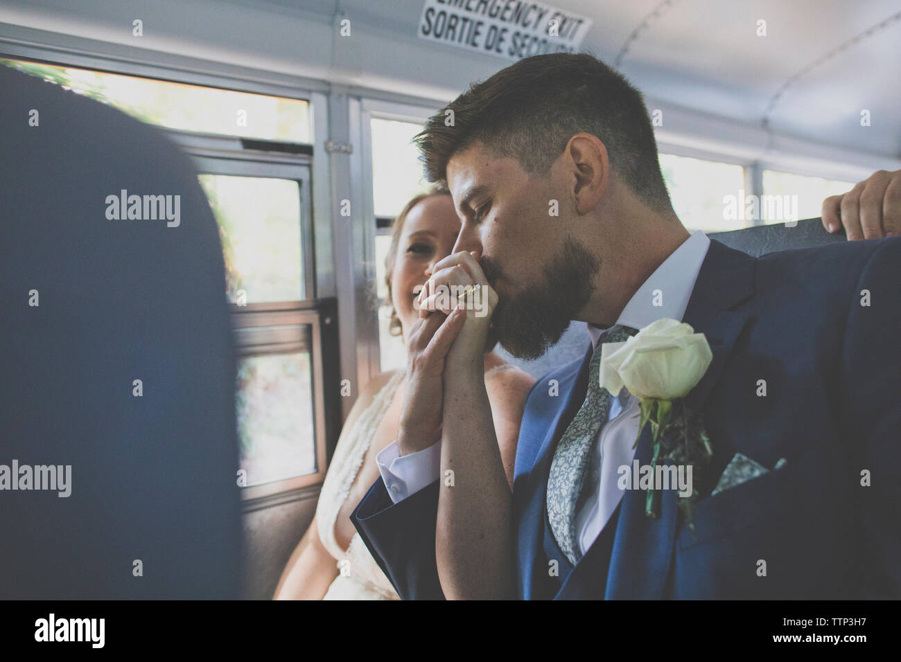Il marito baciare sposa sposa la mano mentre è seduto in bus durante la cerimonia nuziale Foto Stock