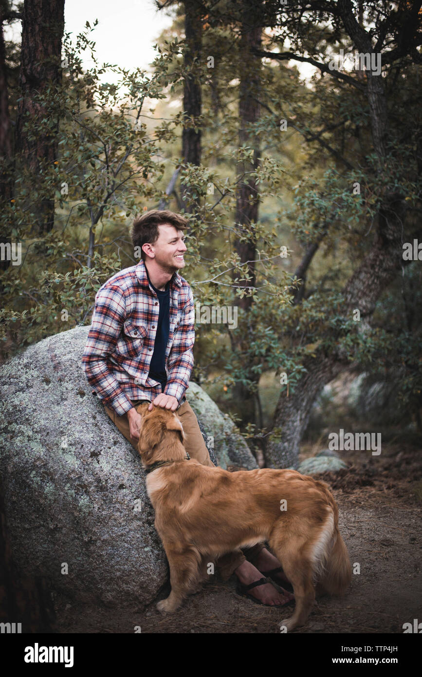 L'uomo con il cane che guarda lontano mentre appoggiata sulla roccia nella foresta Foto Stock