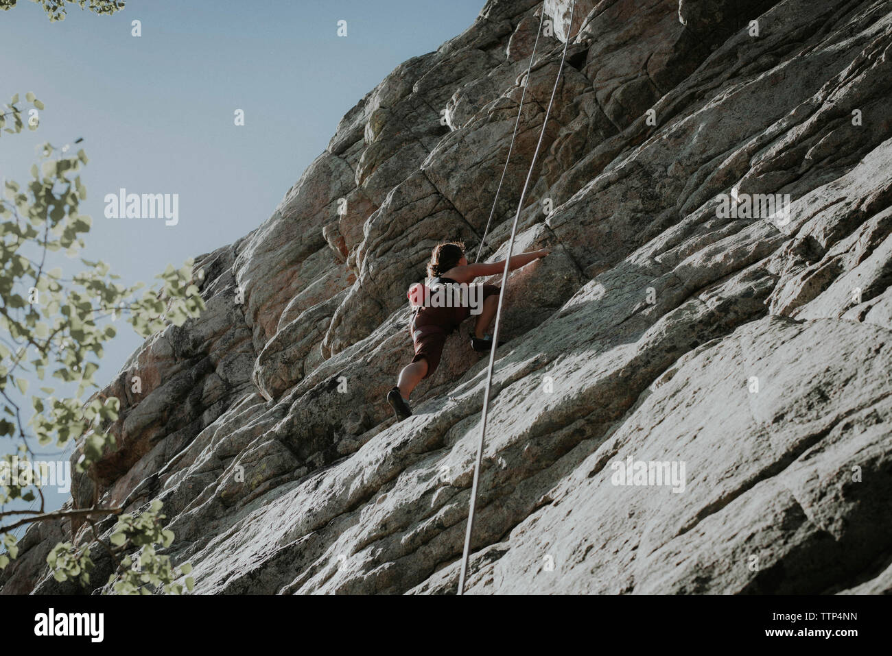 Basso angolo di visione della donna arrampicata in montagna contro il cielo chiaro Foto Stock