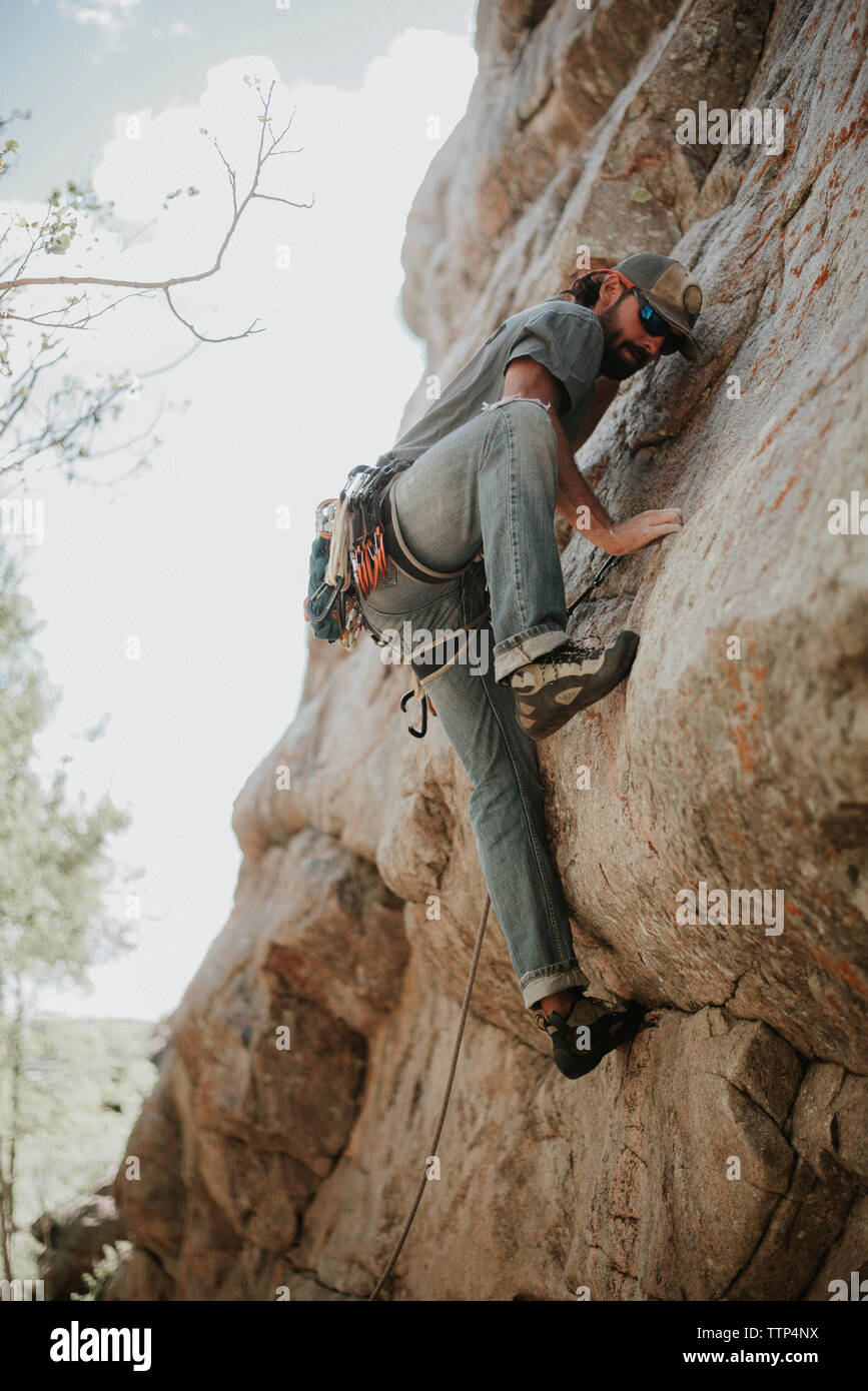 Basso angolo di visione dell'uomo arrampicata in montagna Foto Stock