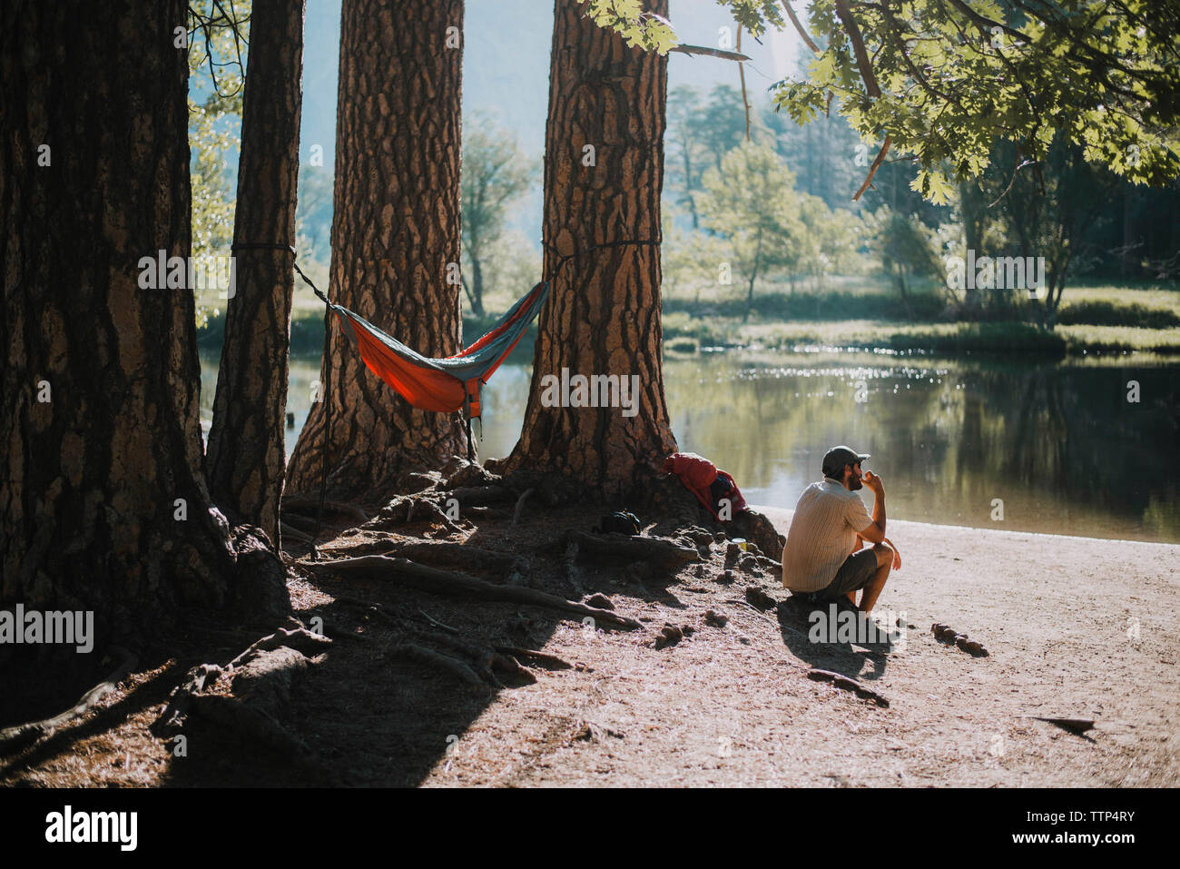 Riflessivo uomo seduto dal lago al Parco Nazionale di Yosemite Foto Stock