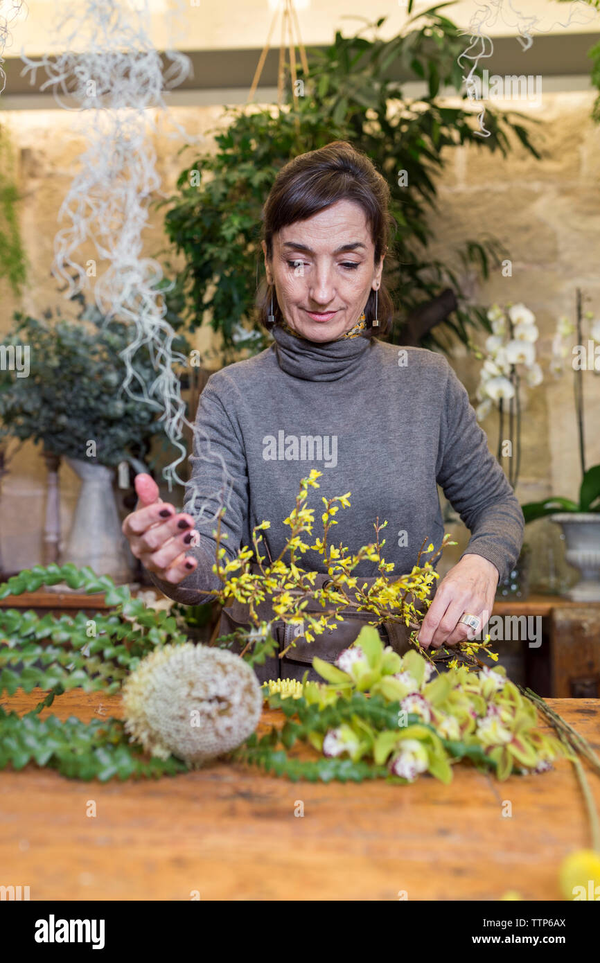 Senior donna preparazione di bouquet di fiori al negozio di fiori scrivania Foto Stock