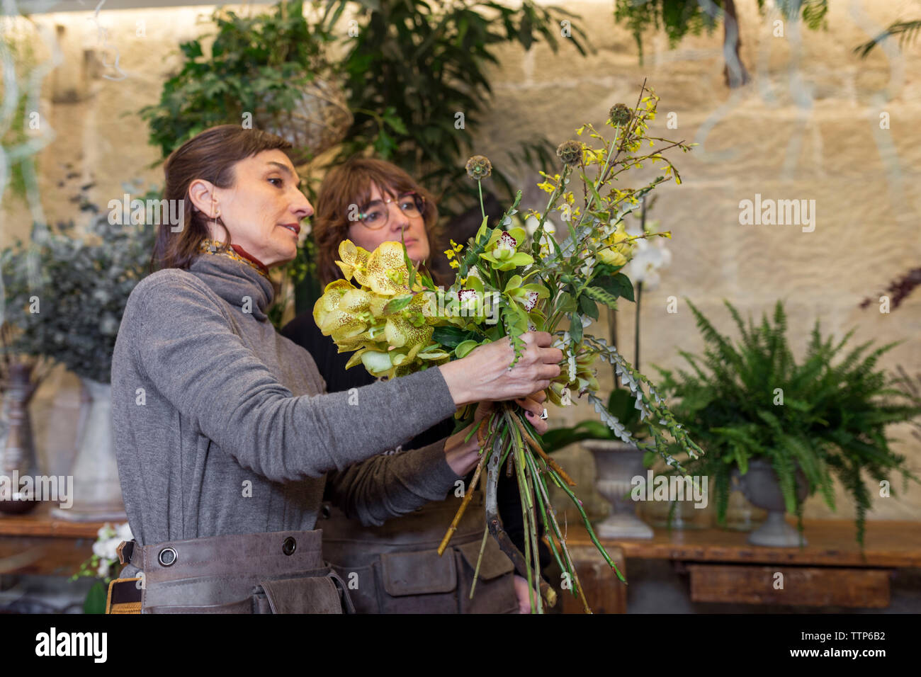 Due donna disponendo bouquet di fiori al negozio di fiori scrivania Foto Stock