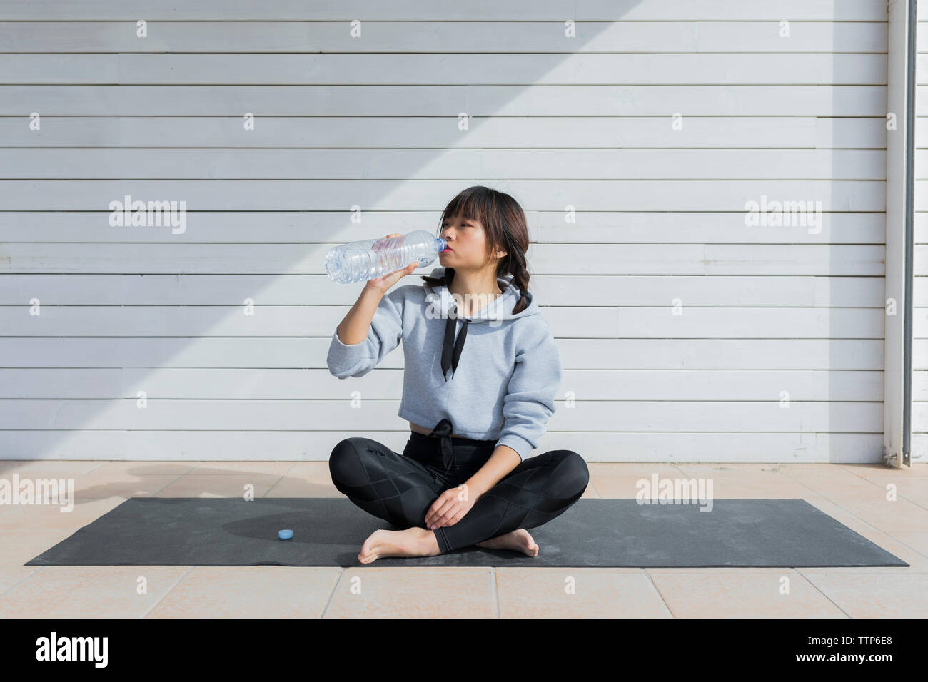 Giovane donna asiatica di bere acqua da bottiglie di plastica in abbigliamento sportivo Foto Stock