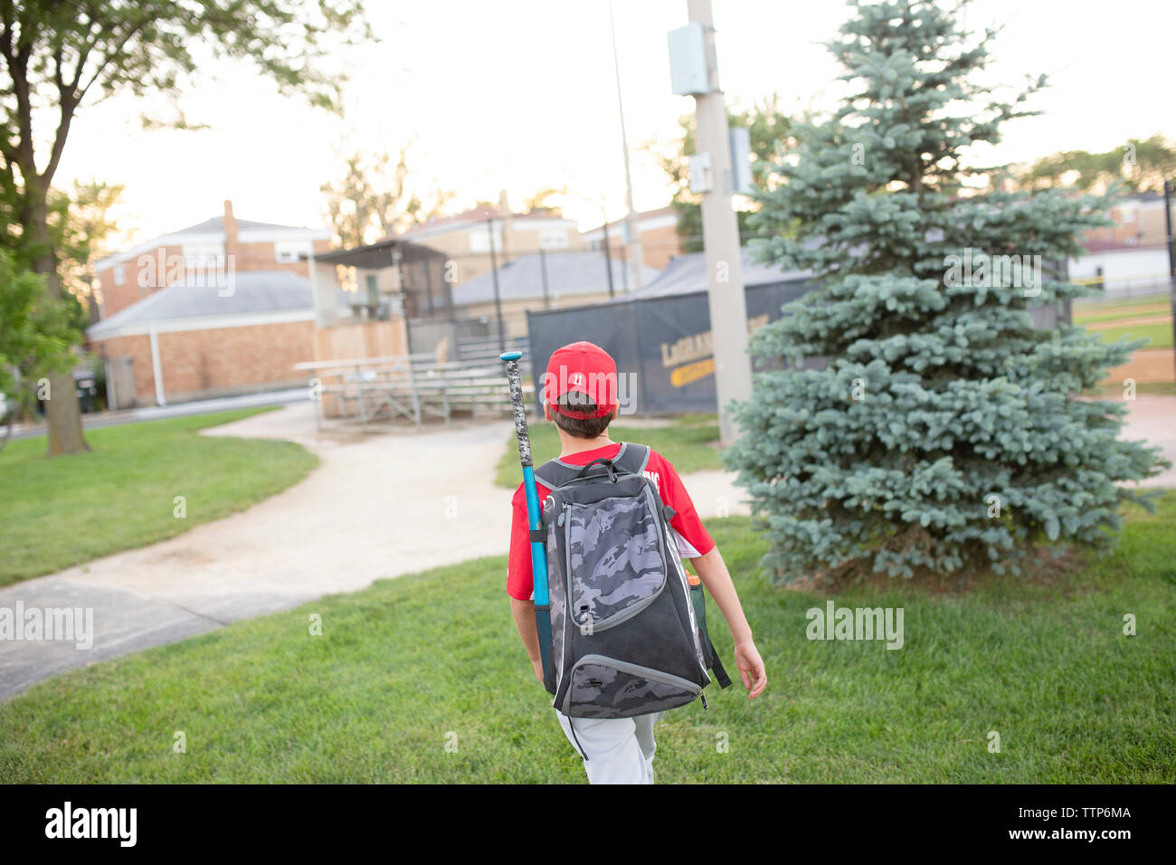 Vista posteriore del giocatore di baseball con zaino walking on Grassy campo da gioco Foto Stock