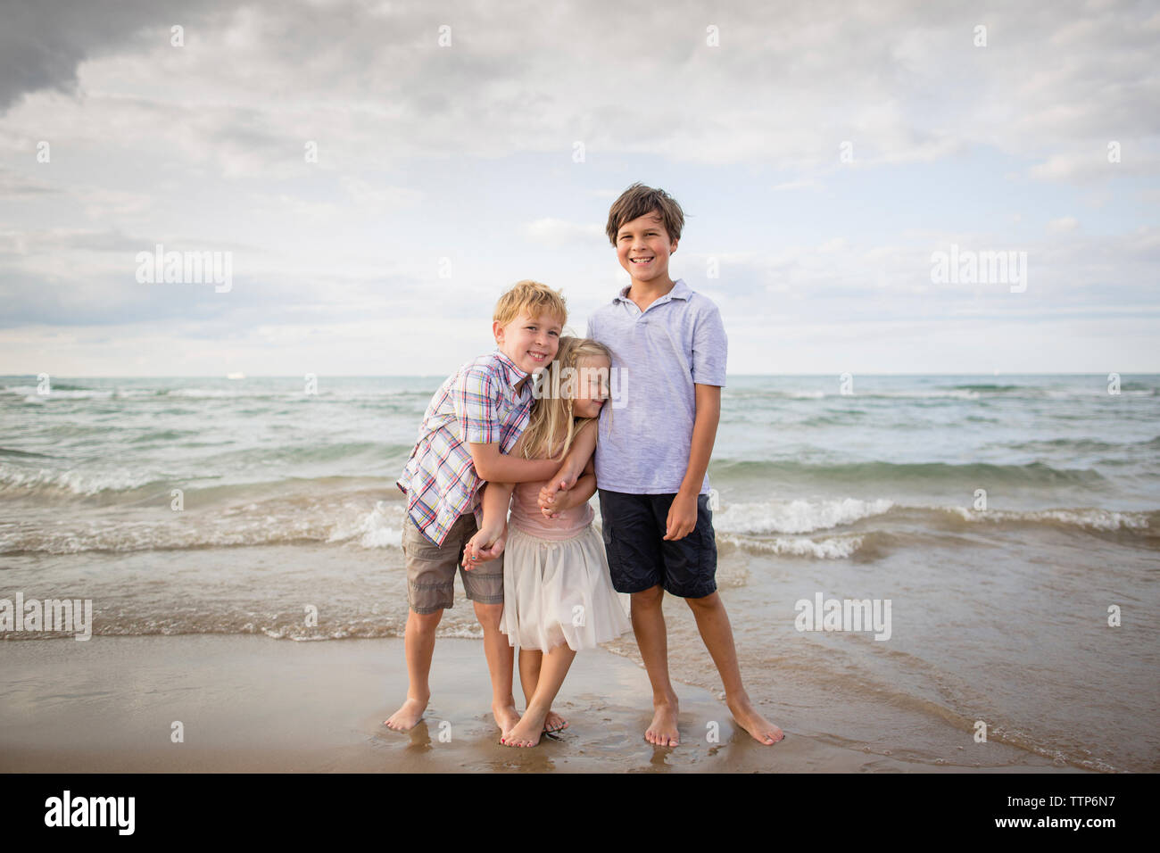 Lunghezza completa di giocoso fratelli permanente sulla riva presso la spiaggia Foto Stock