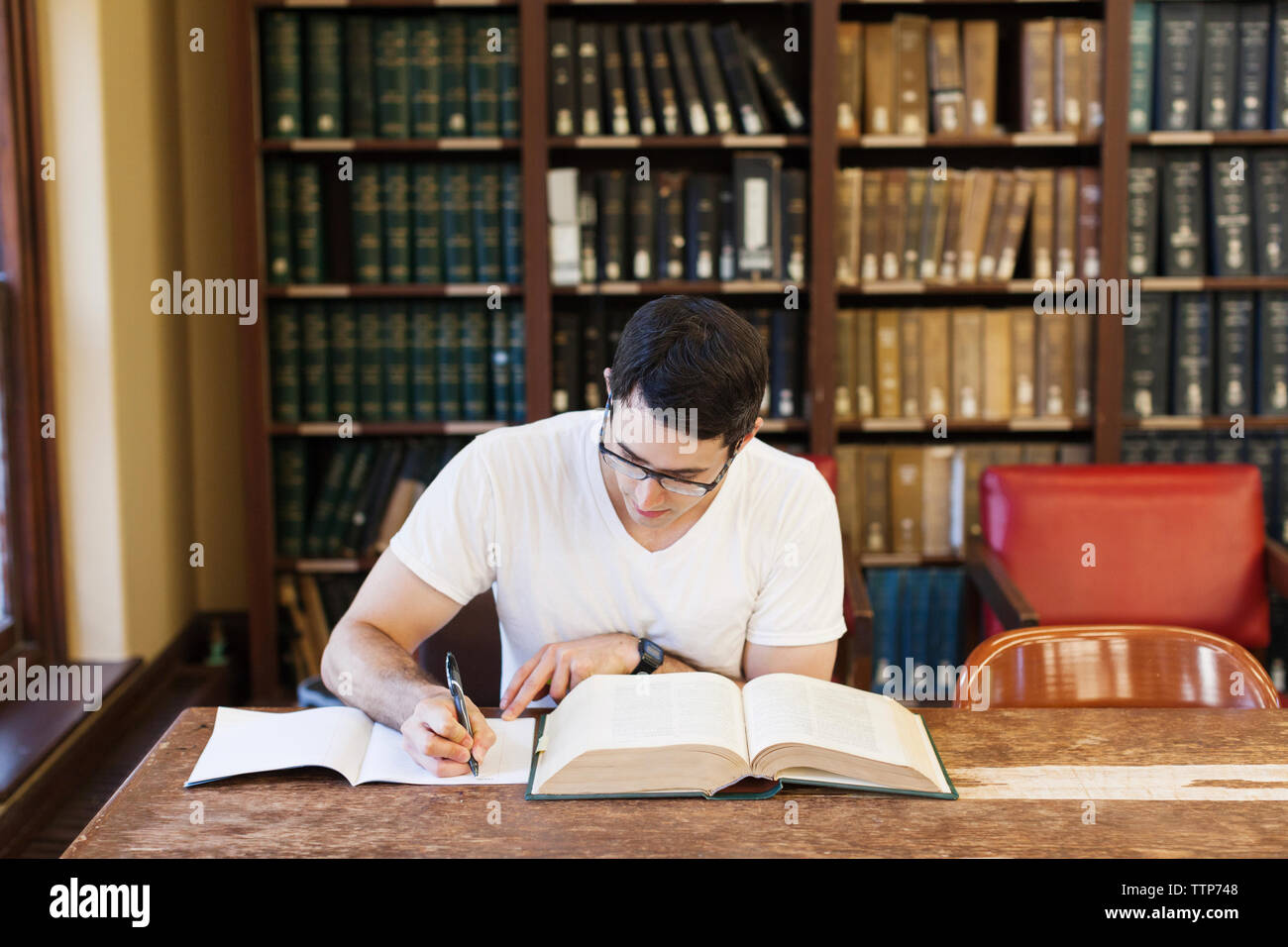 Fiducioso studente maschio studiare in biblioteca Foto Stock
