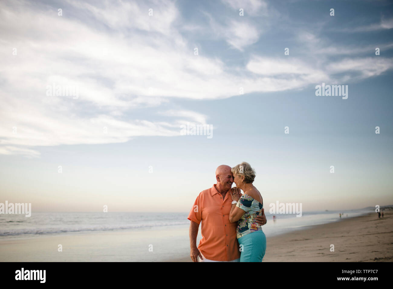 Romantico coppia senior guardando gli uni con gli altri mentre in piedi dal mare contro il cielo durante il tramonto Foto Stock
