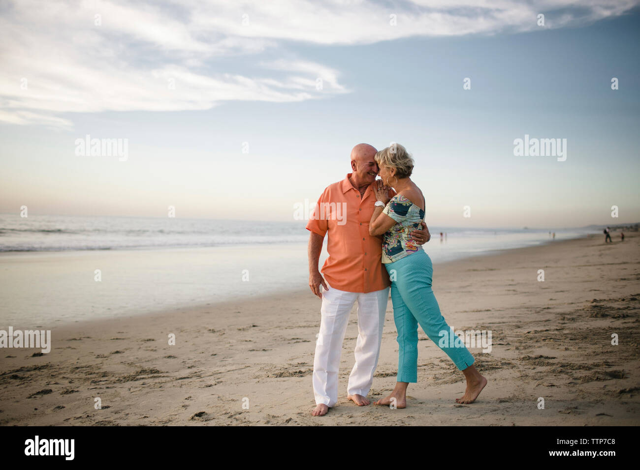 Romantico coppia senior guardando gli uni con gli altri mentre in piedi dal mare contro sky Foto Stock