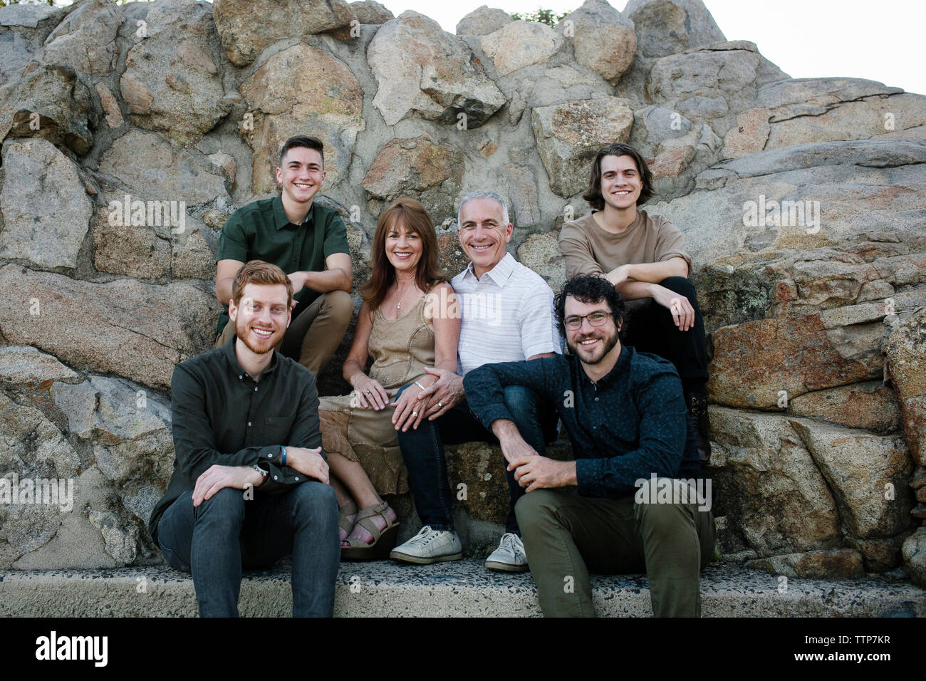 Ritratto di famiglia felice seduto contro le formazioni rocciose a park Foto Stock