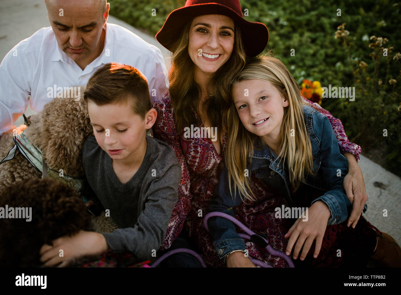 Famiglia di quattro persone con cani seduti insieme abbracciando e sorridente in SoCal Foto Stock