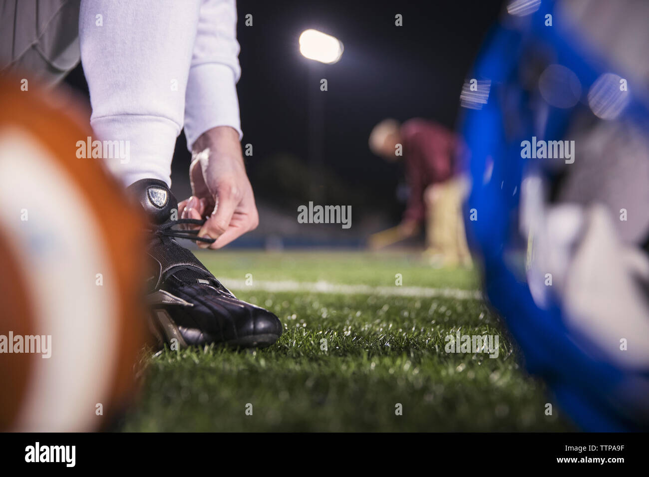 Sezione bassa del giocatore di football americano passalacci di legatura sul campo con pulmann in background Foto Stock