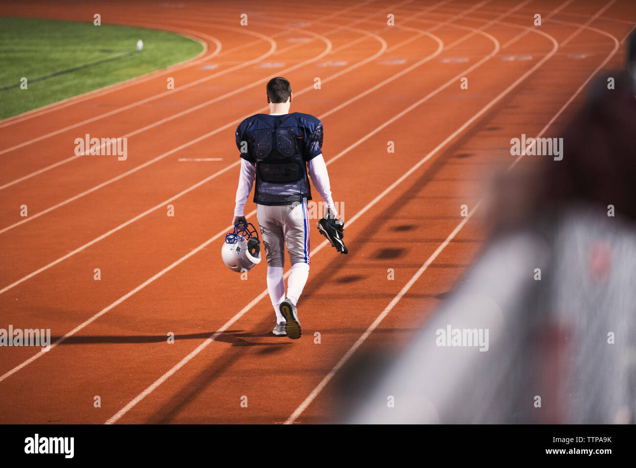 Vista posteriore del giocatore di football americano camminando sulla via dello sport in stadium Foto Stock