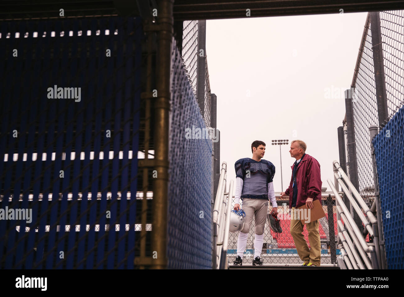 Pullman a discutere con il giocatore di football americano a stadium visto attraverso l'ingresso Foto Stock