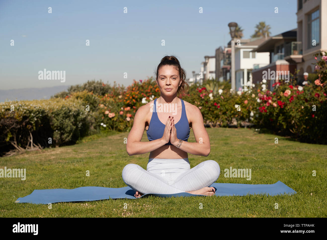 Ritratto di donna con le mani incrociate e a gambe incrociate meditando sul tappeto di esercizio Foto Stock