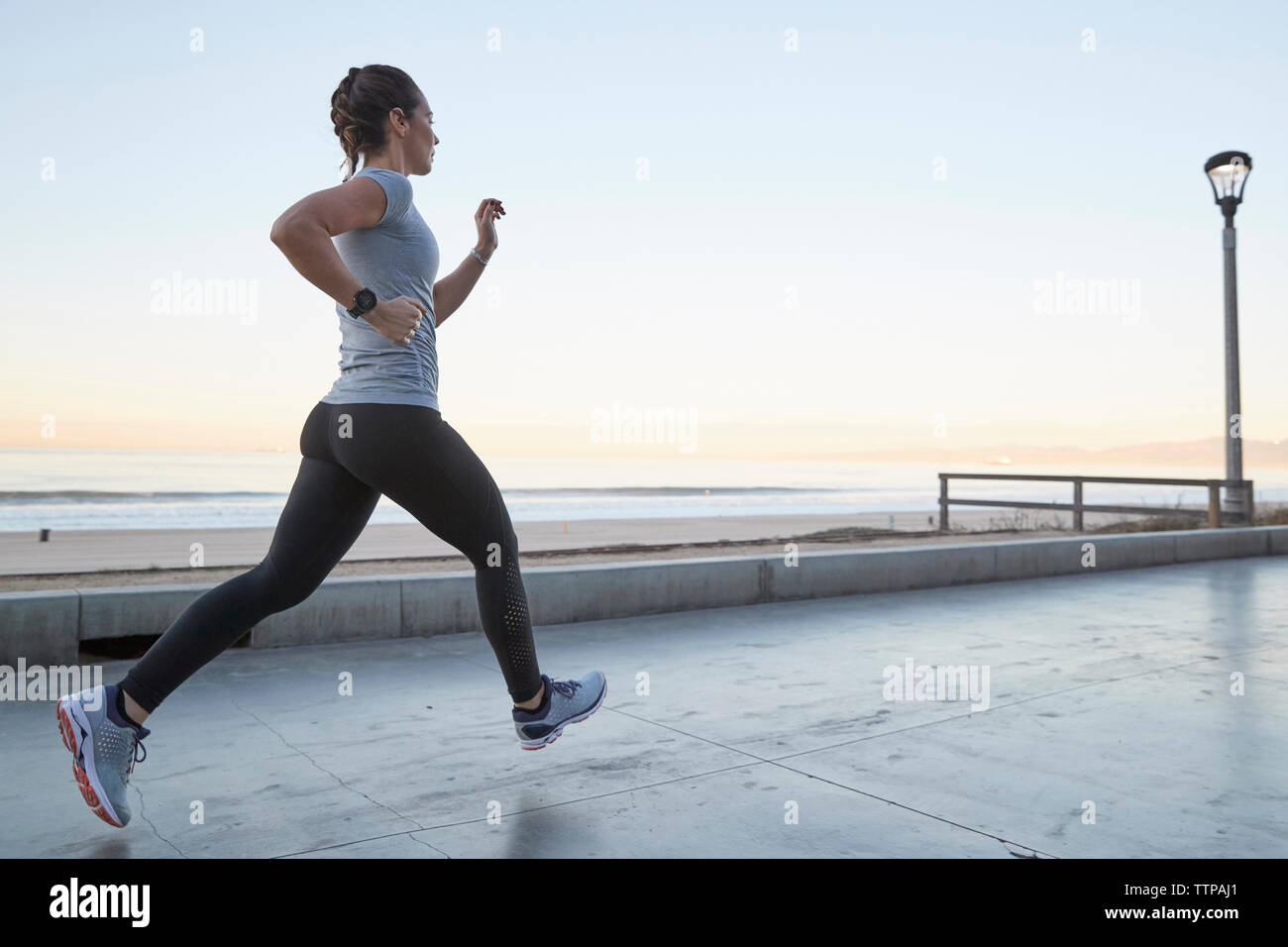 Vista laterale della donna jogging contro il cielo chiaro Foto Stock