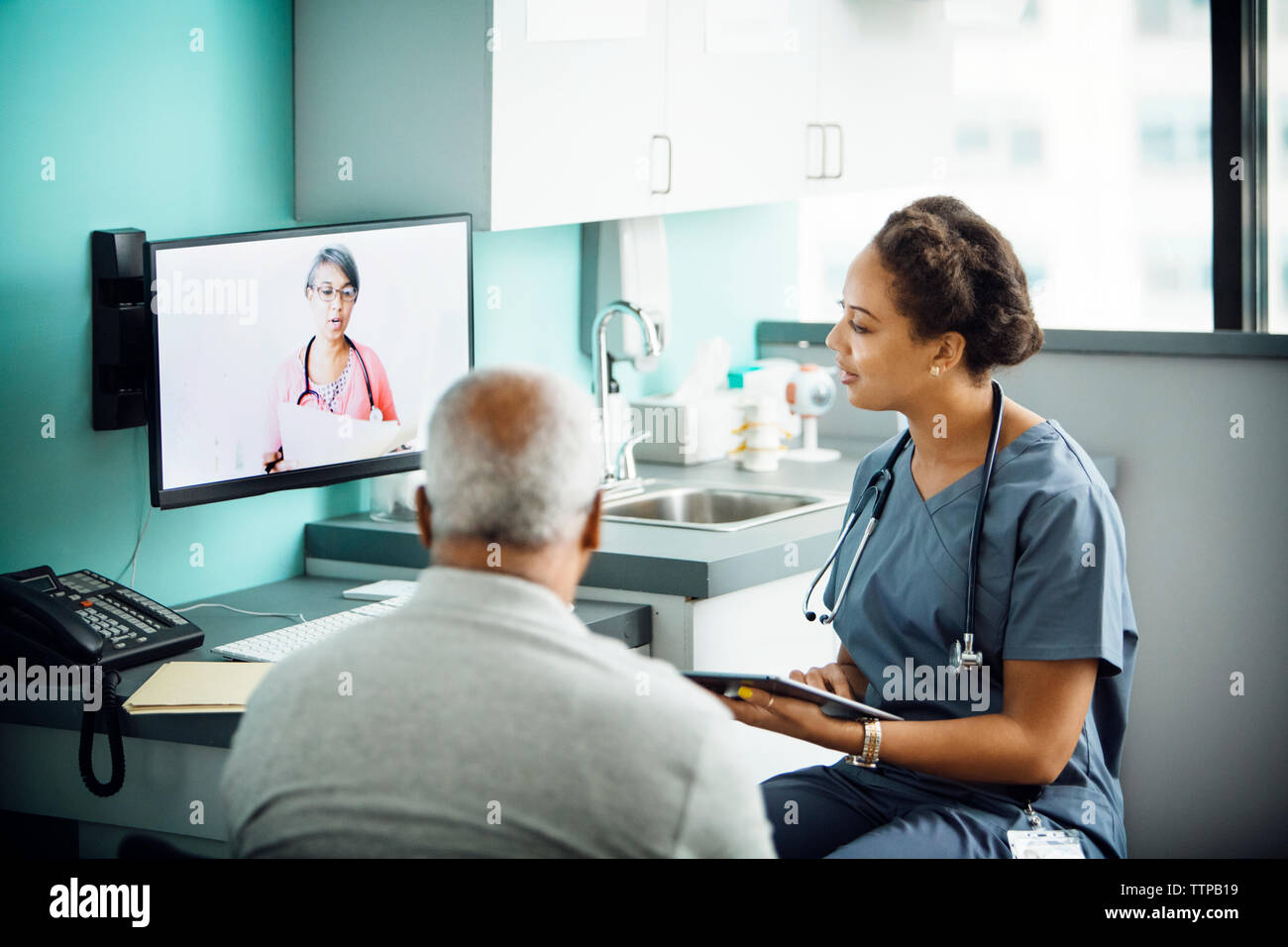 Medico donna discutendo con la collega femmina sulla chiamata in conferenza durante la seduta con il paziente in clinica Foto Stock