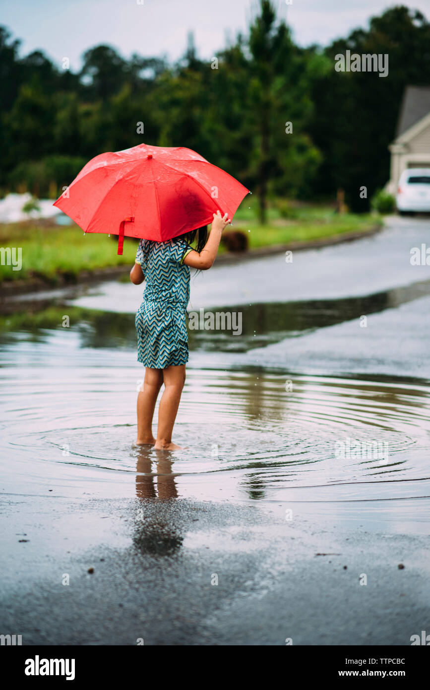 Vista posteriore della ragazza con un ombrello mentre permanente sulla strada Foto Stock
