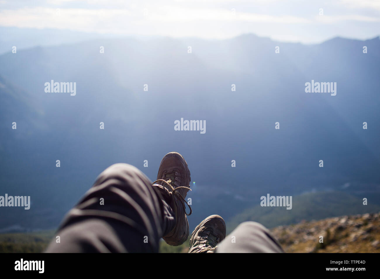 Sezione bassa di un escursionista seduto sulla scogliera contro la montagna Foto Stock