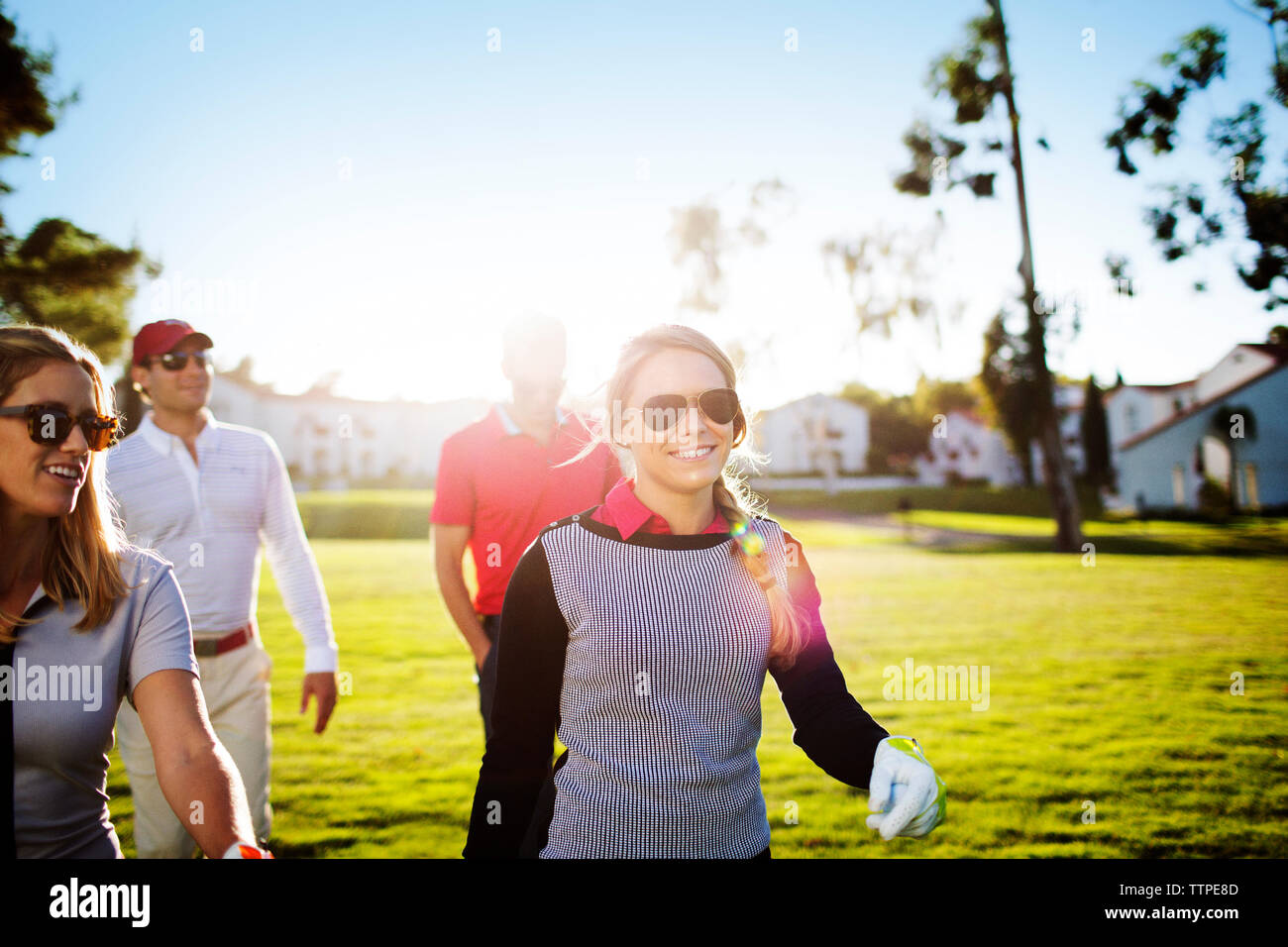 Felice maschio e femmina golfisti camminando sul campo durante la giornata di sole Foto Stock
