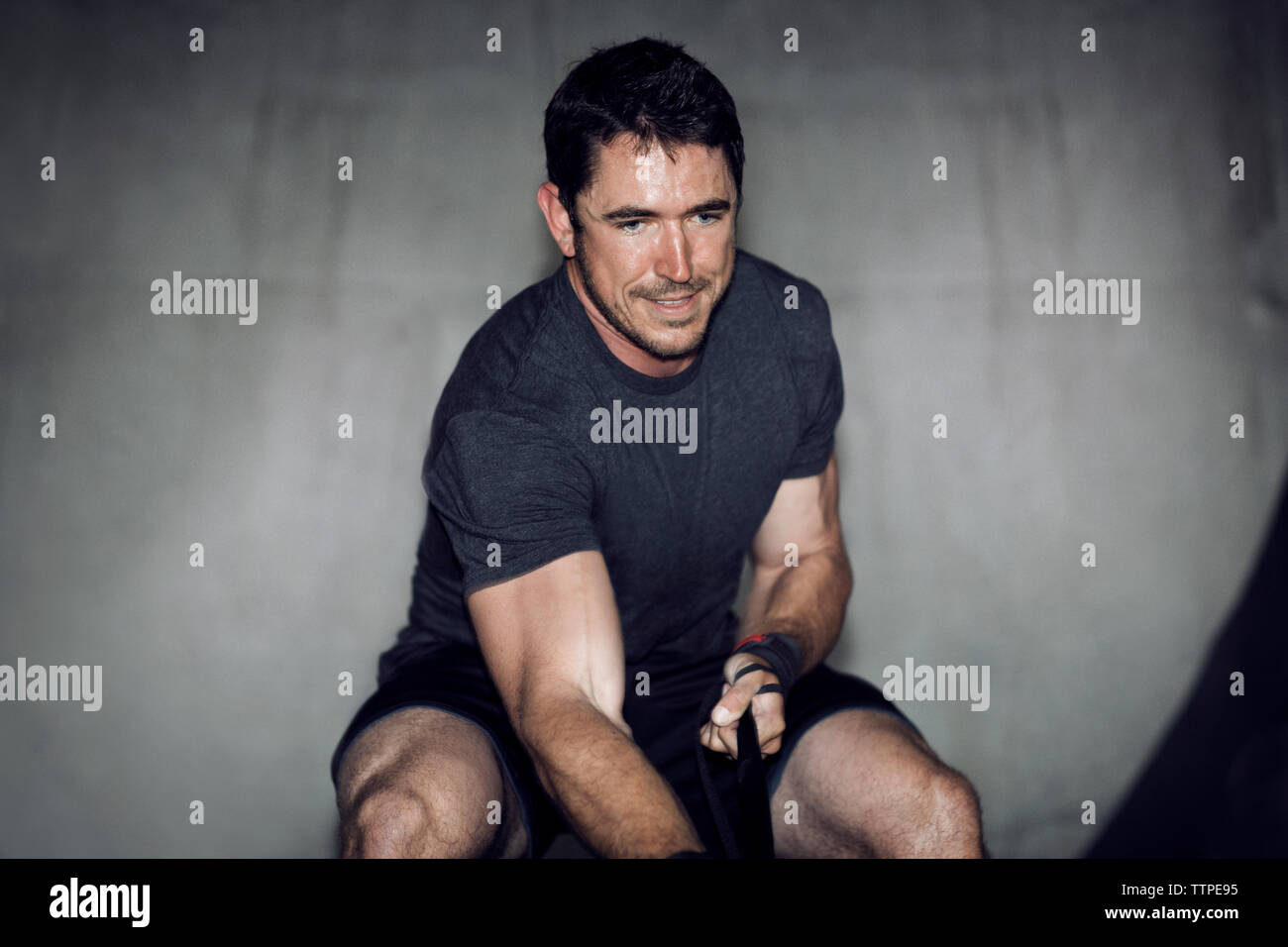 Determinato atleta maschio tirando la cinghia di sospensione in palestra Foto Stock
