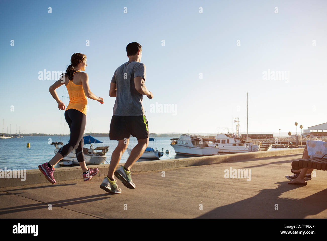 Vista posteriore del maschio e femmina atleti jogging sul molo di porto Foto Stock