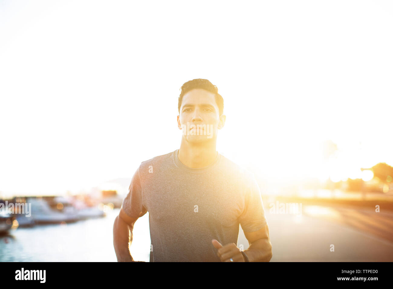 Determinato atleta maschio in esecuzione su pier durante il tramonto Foto Stock