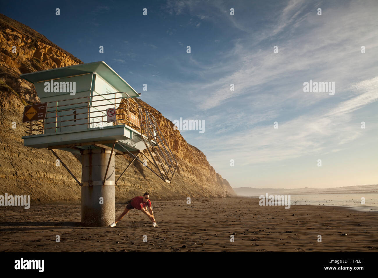 Atleta maschio esercita sulla spiaggia contro sky Foto Stock