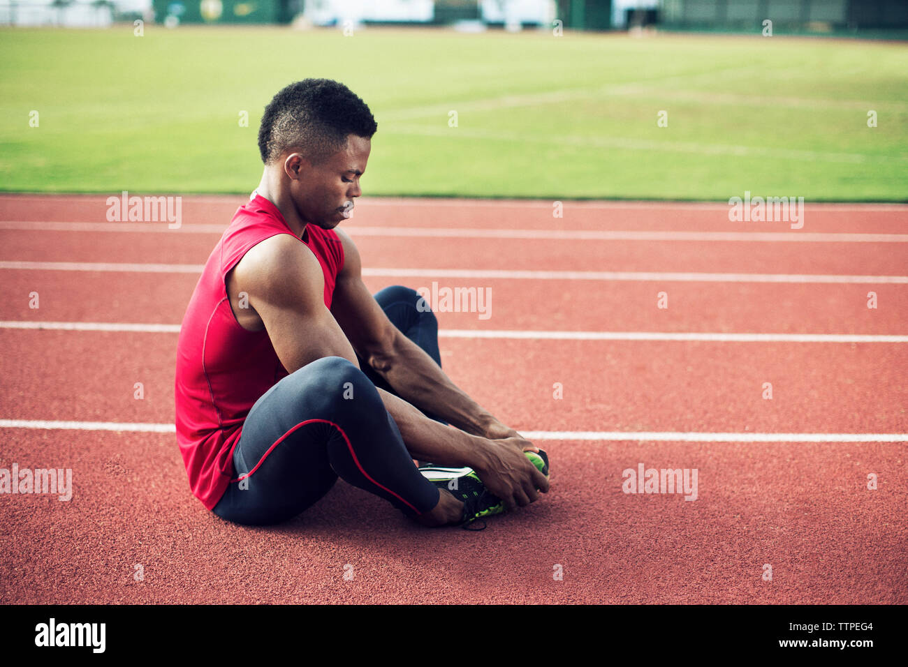 Vista laterale di atleta maschio eseguendo abduttore breve tratto sul campo Foto Stock