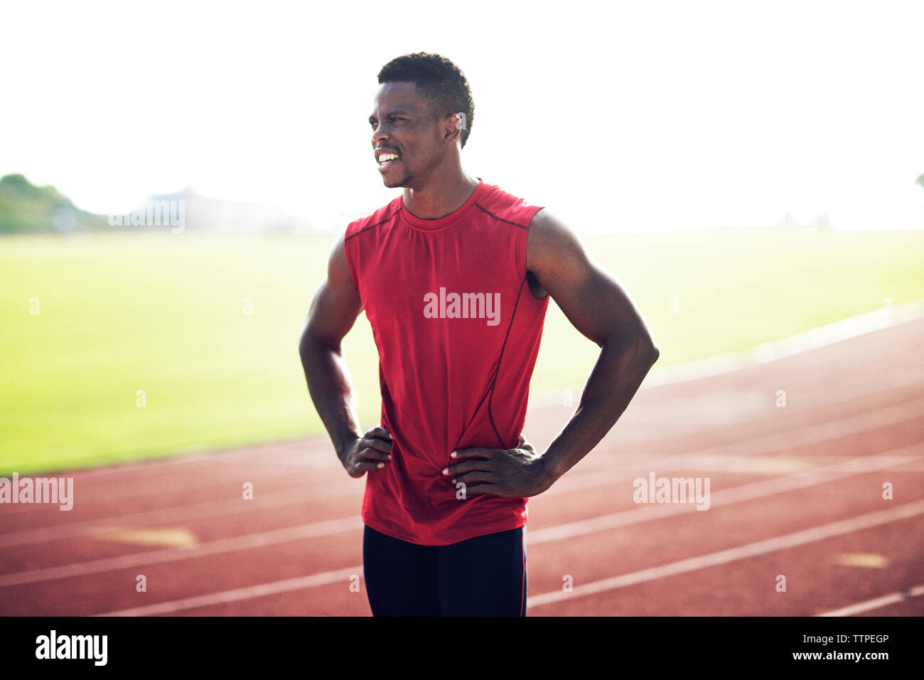 Stanco atleta maschio in piedi con le mani sui hip nel campo Foto Stock