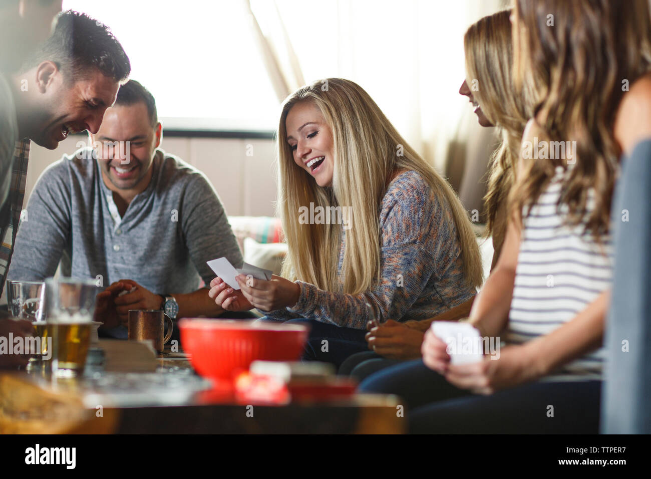 Happy amici guardando a carte mentre gioca in casa Foto Stock