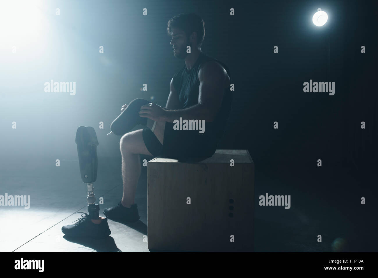 Adattativo regolazione atleta apparecchiature protesiche seduti sulla scatola in palestra Foto Stock