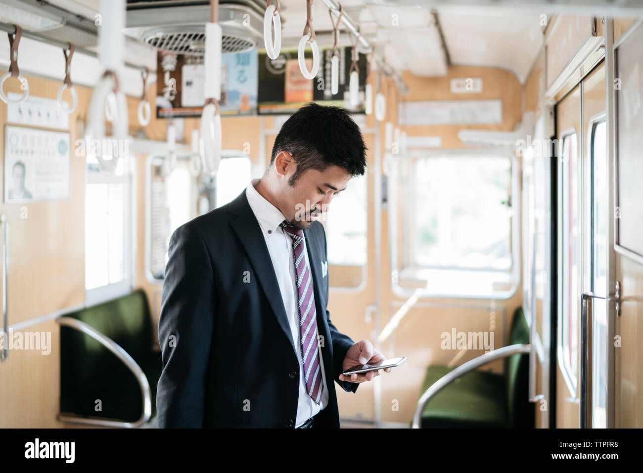 uomo d'affari che usa lo smartphone mentre è in treno Foto Stock
