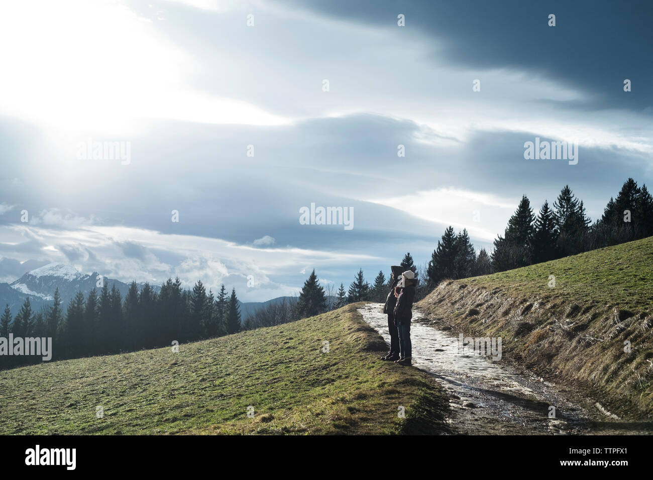 L uomo e la donna in piedi sulla montagna contro il cielo nuvoloso Foto Stock
