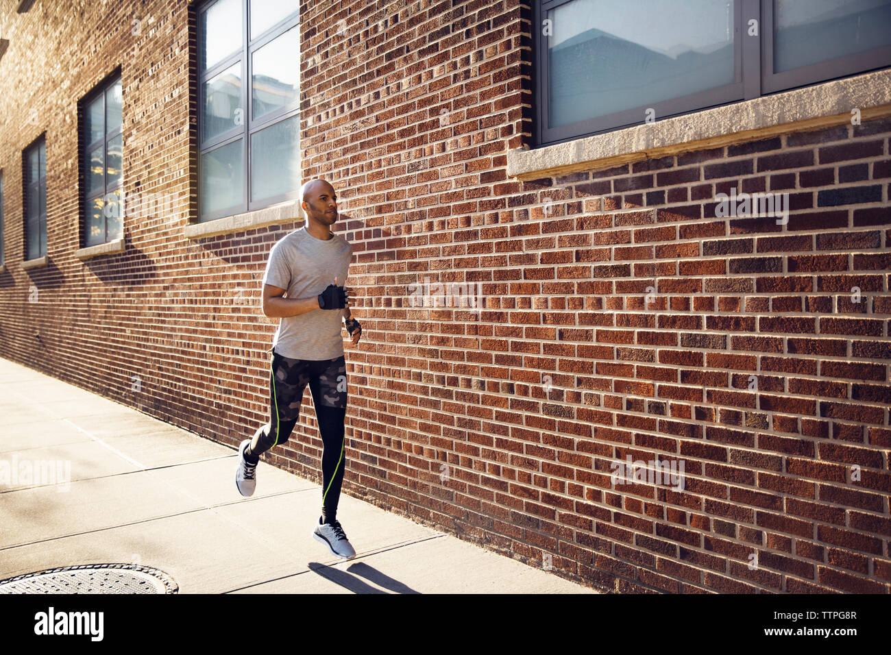 Determinato atleta maschio in esecuzione sul sentiero da un muro di mattoni Foto Stock
