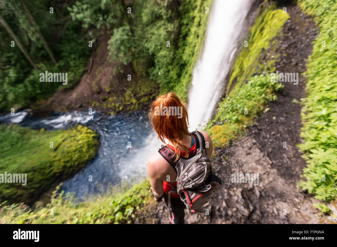 Elevato angolo di visione femminile di escursionista con zaino in piedi su Eagle Creek Trail contro cadute di Tunnel Foto Stock