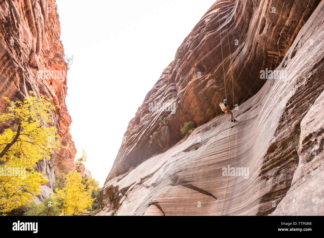 Basso angolo di visione dell'uomo rappelling contro il cielo chiaro Foto Stock