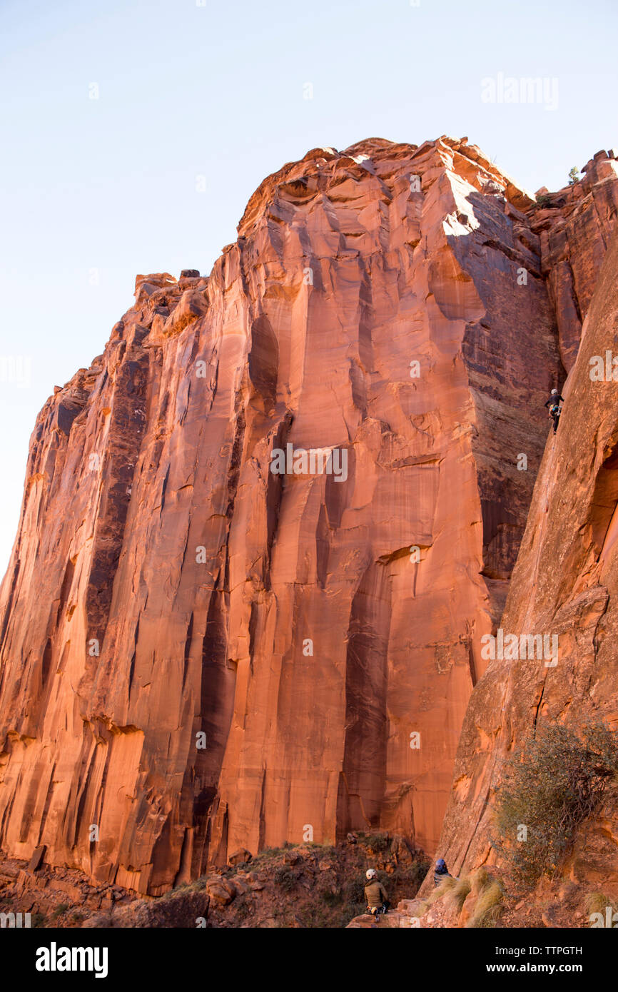 Basso angolo di visione femminile di escursionista climbing mountain contro il cielo chiaro Foto Stock