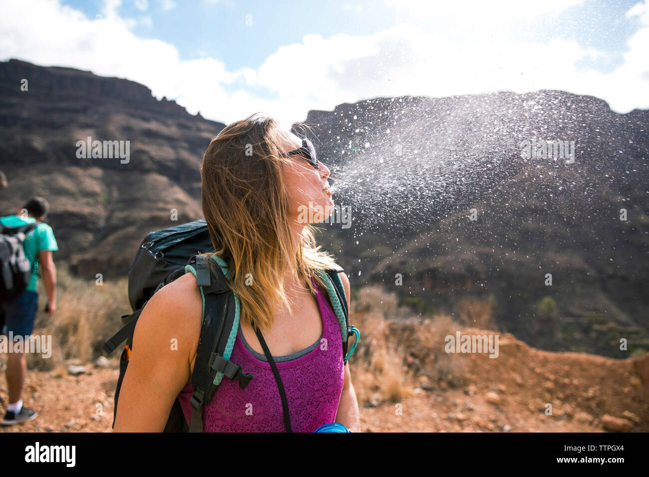 Backpacker femmina che sputano acqua contro le montagne presso il desert Foto Stock
