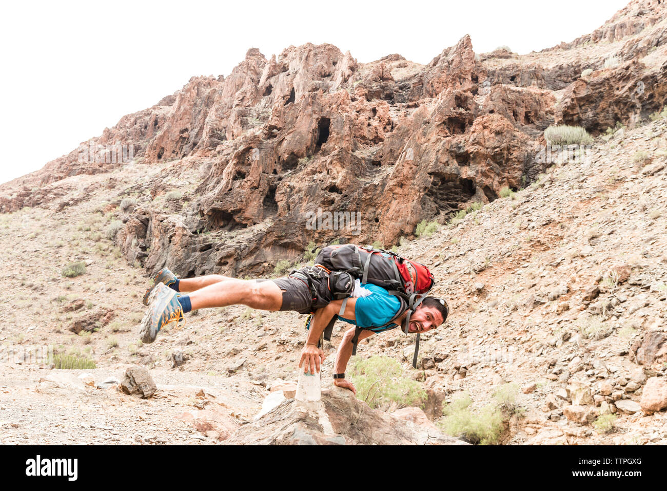 A piena lunghezza Ritratto di backpacker urlando mentre il bilanciamento sulle rocce al desert Foto Stock