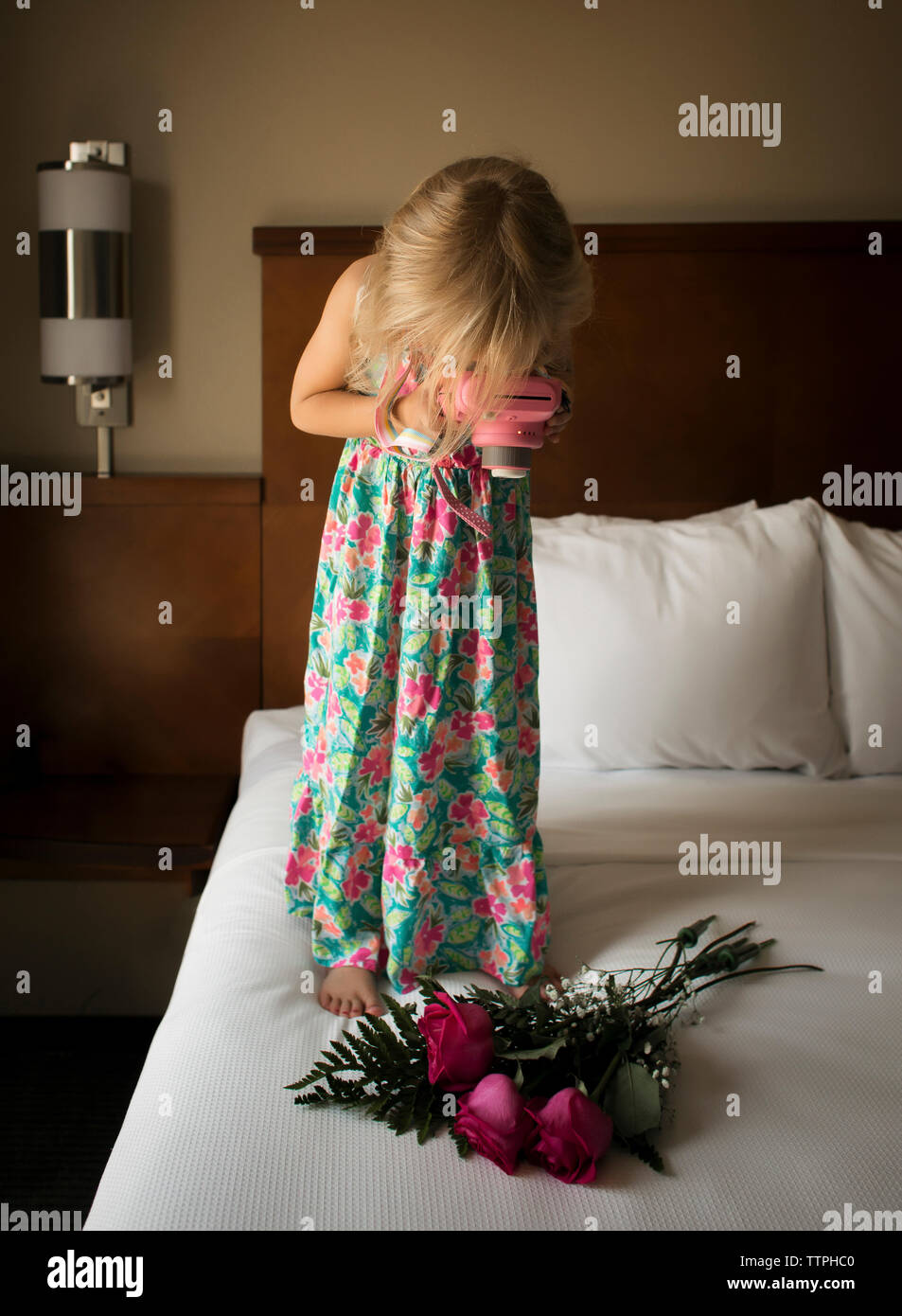 Ragazza di fotografare le rose mentre si sta in piedi sul letto di casa Foto Stock