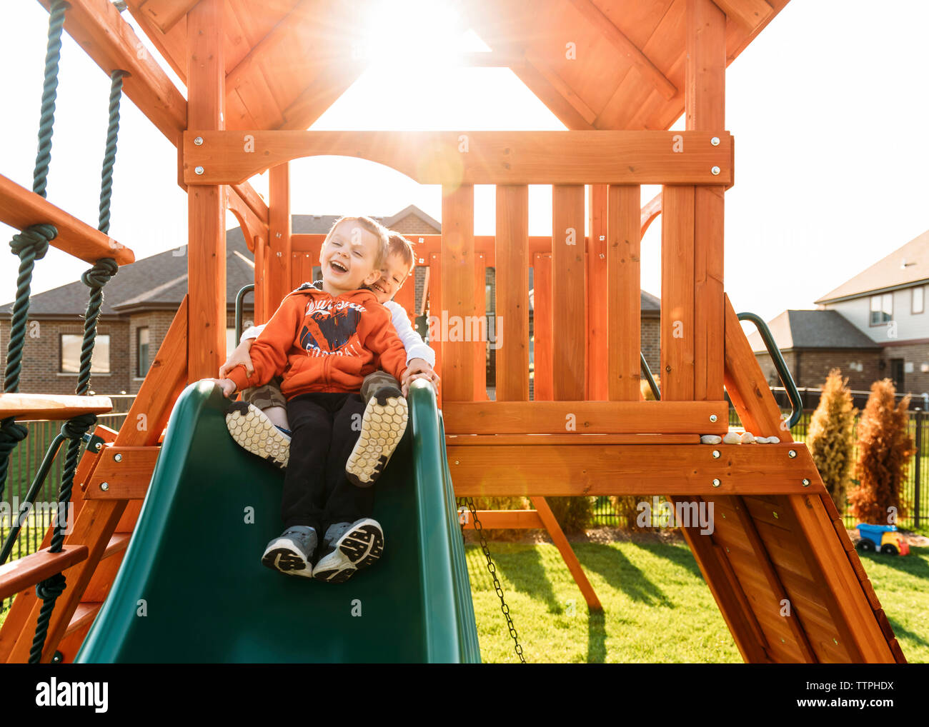 Fratelli giocando sulla slitta in posizione di parcheggio Foto Stock