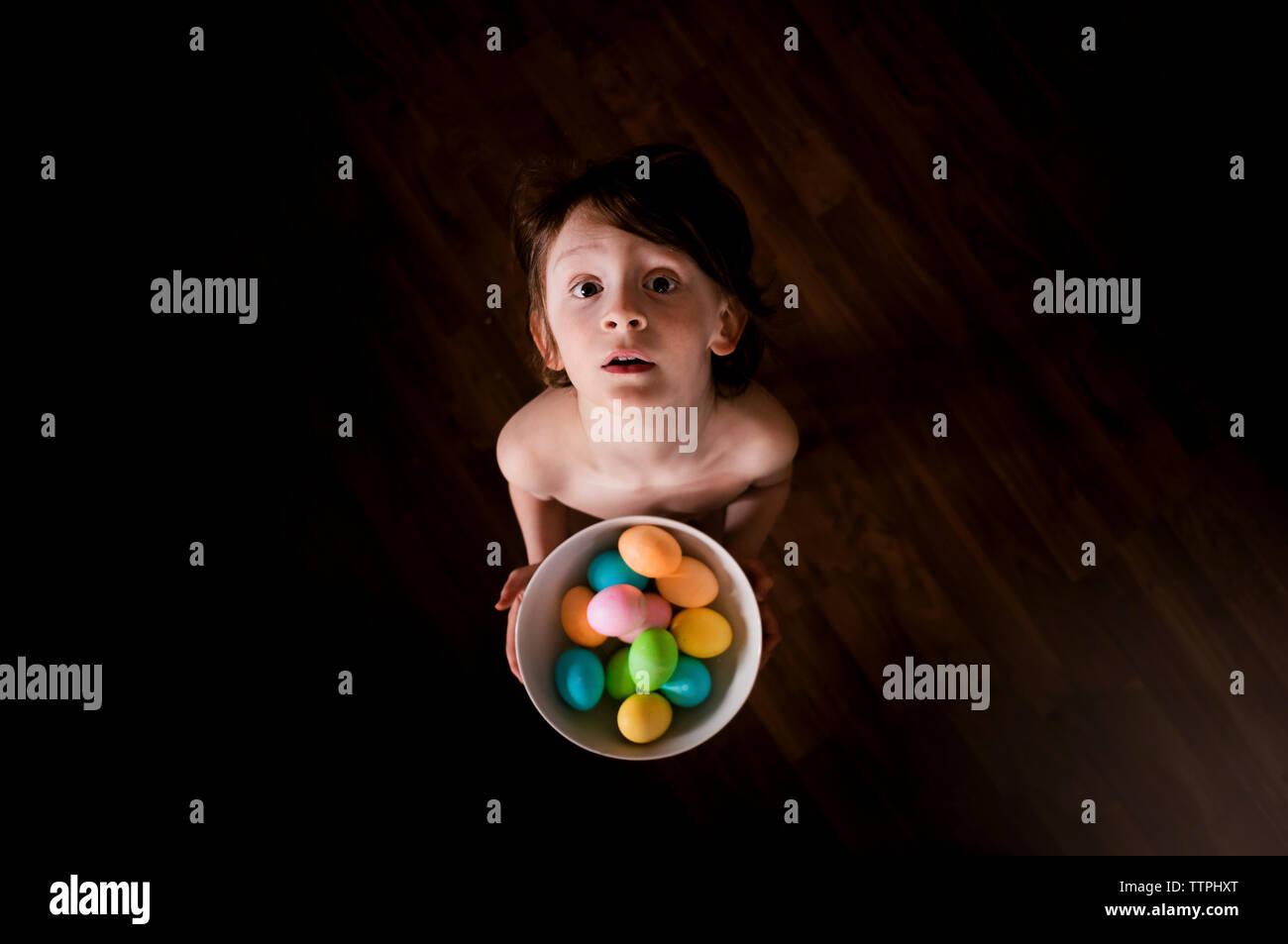 Un piccolo ragazzo giovane azienda una ciotola di colorate Uova di Pasqua Foto Stock