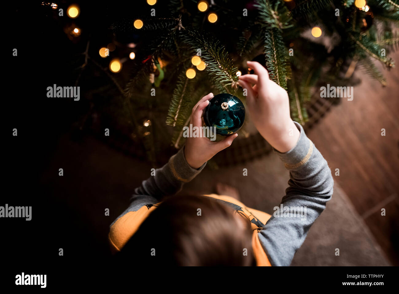 Un giovane ragazzo che guarda verso il basso in un albero di Natale ornamento Foto Stock