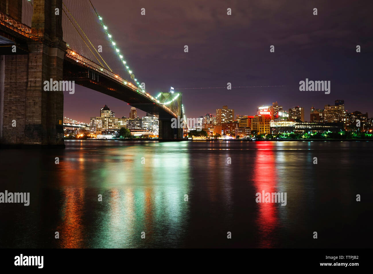 Illuminata Brooklyn ponte sul fiume contro la città illuminata Foto Stock